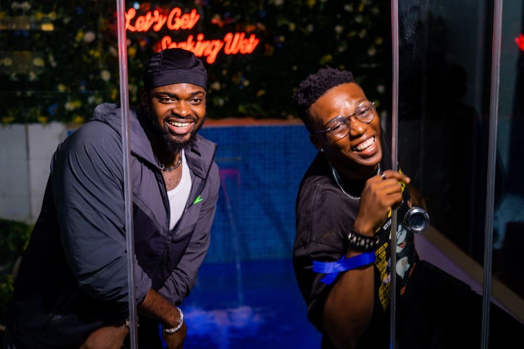 Two guests smiling behind glass at a neon-lit lounge