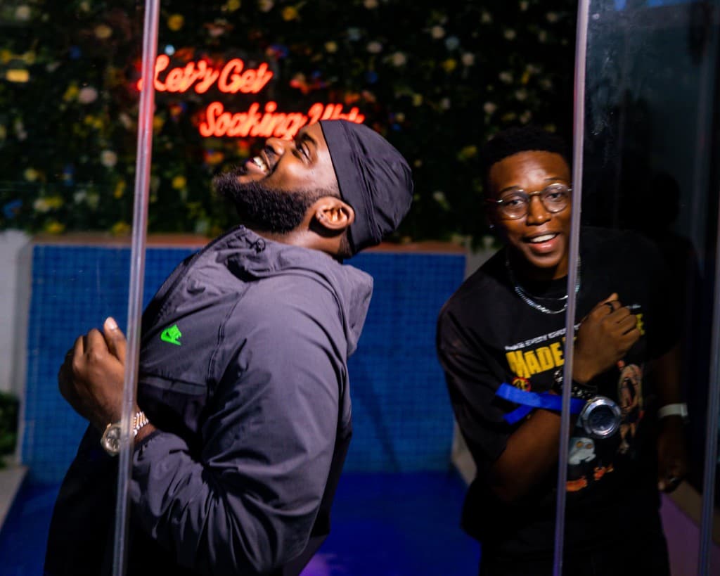 Two guests smiling by the neon wall at Cafeteria